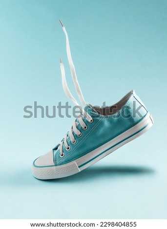 A classic blue sneaker floats in the air on a blue background. Royalty-Free Stock Photo #2298404855