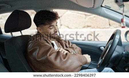 Young arab man sitting on car dancing at street