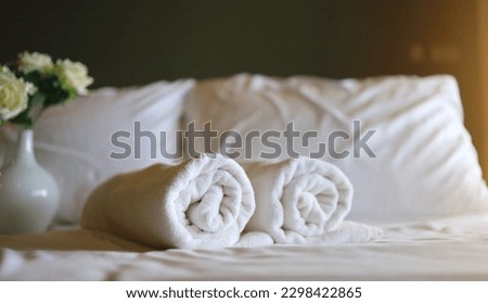 White towel roll on a white pillow and bed decoration in bedroom interior to vintage style hotel. vacation concept.