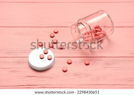 Bottle with hormonal pills on pink wooden background Royalty-Free Stock Photo #2298430651