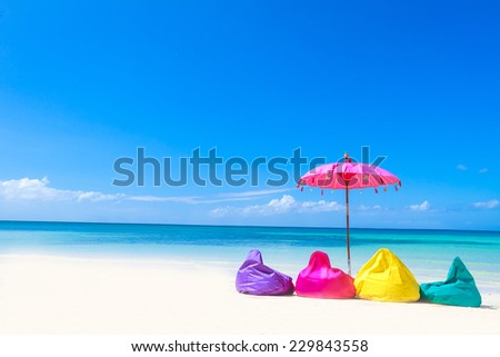colorful pillows and bright umbrella on tropical sea and beach background, vacation in tropics
