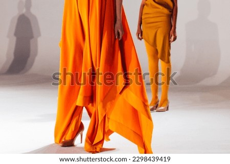 Fashion model woman wearing bright long orange yellow summer dress. Casual stylish female clothes concept. Fashion week catwalk fashion details