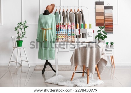 Interior of stylish atelier with tailor's workplace, clothes and mannequin Royalty-Free Stock Photo #2298450979