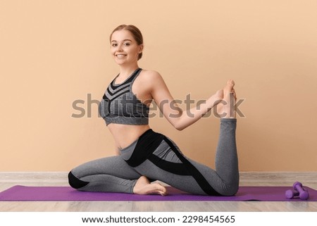 Sporty young woman doing yoga indoors