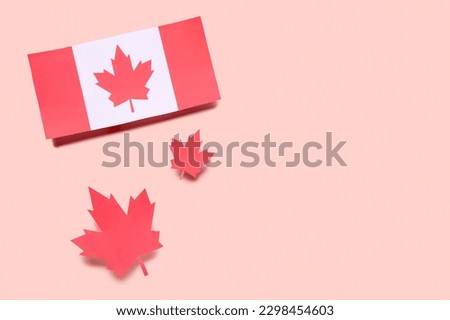 Flag of Canada with paper maple leaves on pink background