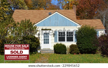 Sold Real Estate (another success let us help you buy sell your next home) sign on front yard lawn of suburban house residential neighborhood USA fall season