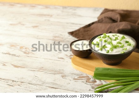 Composition with sour cream and sliced green onion on wooden table Royalty-Free Stock Photo #2298457999