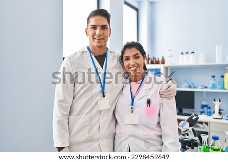 Man and woman scientists partners hugging each other at laboratory