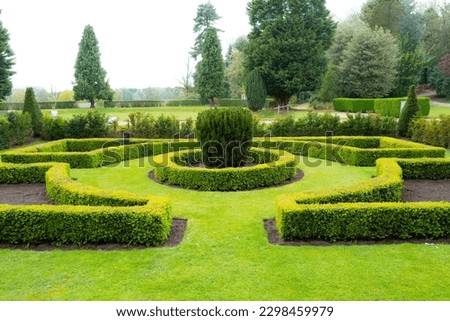 Ornate and well kept garden maze seen at a once stately home now a luxury hotel in the UK. Royalty-Free Stock Photo #2298459979