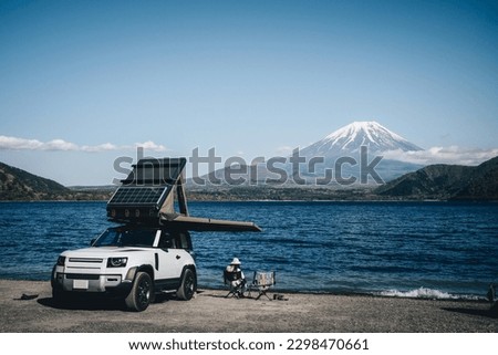White 4x4 overland car with rooftop tent and awning at the beach and a lake with a view of Mountain Fuji, Japan.  Royalty-Free Stock Photo #2298470661