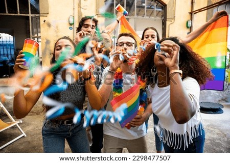 Group of friends celebrate pride with flags and streamers by dancing at a demonstration for support for equality - People having fun together Royalty-Free Stock Photo #2298477507