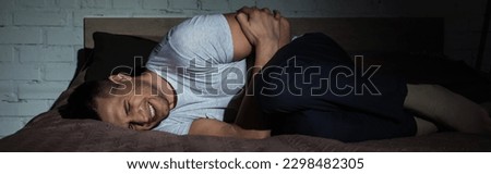 young man with closed eyes suffering from post traumatic stress disorder while lying on bed at night, banner