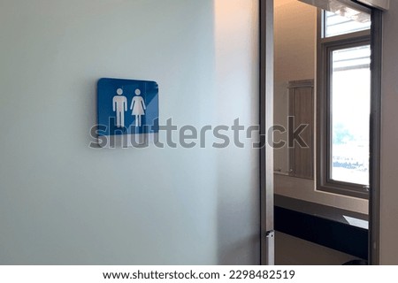 Public Restroom With Male And Female Toilet Sign On Glass Wall.