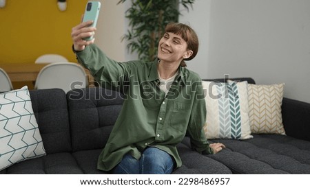 Young caucasian woman taking selfie picture with smartphone at home