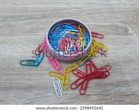 isolated colorful stationery paper clips in the can at wooden working table. Selective focus