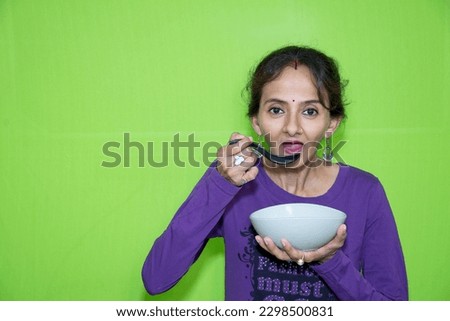 A smart and cute girl eating soup with sausage, a bowl, and a glass spoon in her right hand against a green screen. This shots is ideal for use in commercials and editorials and is ready to be used!