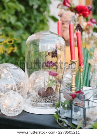 Vintage decor. Cloche glass cap with roses and peonies, glass balls, glass boxes with flowers, red candles in gold candlesticks.