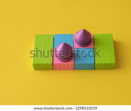 Closeup above view picture of colourful wooden toy blocks arranged against a yellow background.