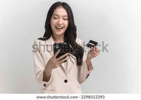 Portrait photo of young beautiful Asian woman feeling happy or surprise shock and looking at smart phone and credit card on white background can use for advertising or product presenting concept.