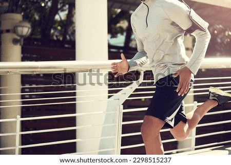 Running will make your body stronger. an unrecognizable man running on a bridge in the city. Royalty-Free Stock Photo #2298515237