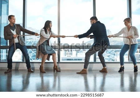 Take matters into your own hands. a group of businesspeople pulling on a rope during tug of war in an office. Royalty-Free Stock Photo #2298515687