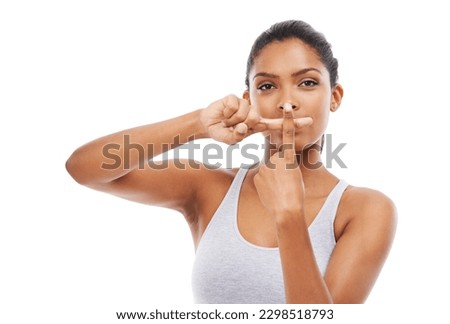 Saying no. A young woman in gym clothes with her fingers crossed and pressed against her mouth.