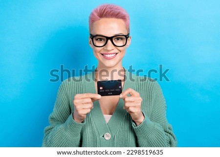 Portrait photo of charming banker promoter woman pink dyed short hairdo stylish glasses hold debit card isolated on blue color background