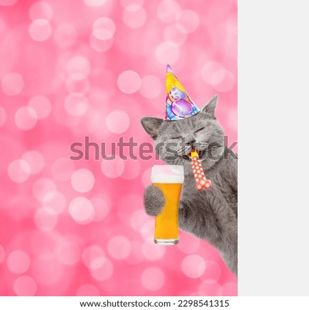 Happy cat wearing party cap blows in party horn, holds glass of beer and looks from  behind empty white banner.  Shade trendy color of the year 2023 -Viva Magenta background. Empty space for text