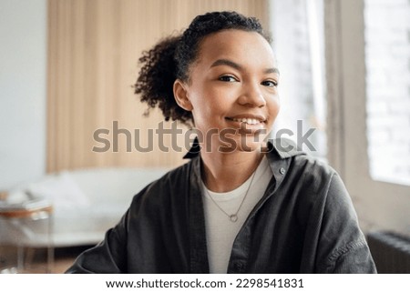 Portrait of a cute and smart young woman with a curly beautiful smile looking at the camera.
