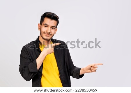 a medium shot of a smiling casual young Asian man pointing to the left with his hand with two hands fingers wearing black clothes shirt yellow t shirt isolated over white background positive human emo