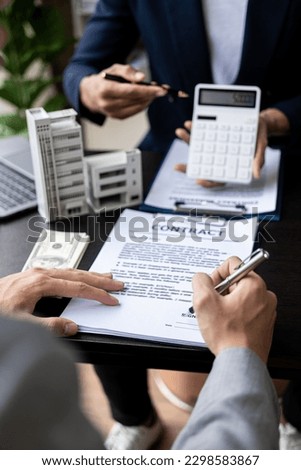 Real estate agents discuss the terms of the home purchase contract and ask the client to sign documents to legally contract the sale of the house with insurance.