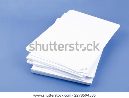 Stack of blank A4 paper sheets on blue background. Royalty-Free Stock Photo #2298594535