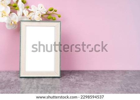 Blank picture frame with white orchid flower on pink color background with copy space and clipping path for the inside.