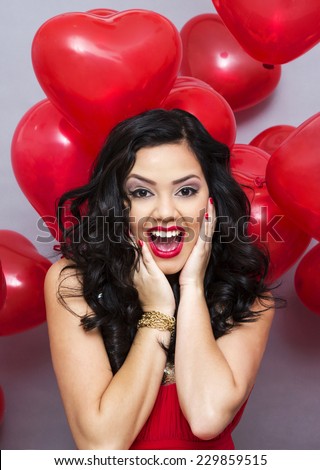 Fashion girl model posing with red heart bright balloons in studio. 