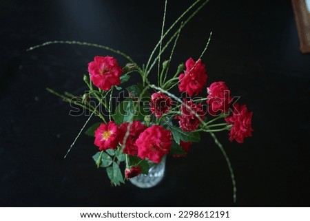 red roses in glass on a wooden black table.