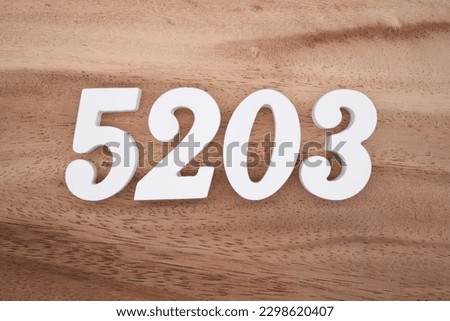 White number 5203 on a brown and light brown wooden background.