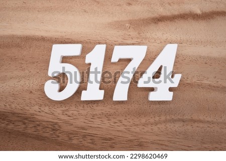 White number 5174 on a brown and light brown wooden background.