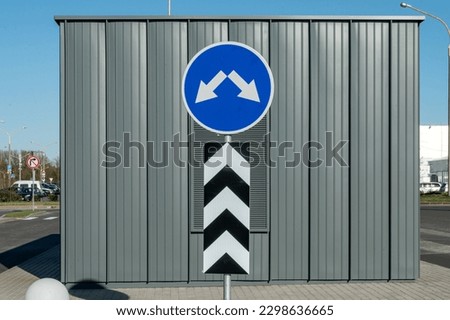 Road traffic sign detour obstacle. A blue sign with two arrows and vertical markings near the building. Additional information sign