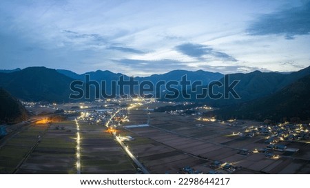 Lights from roads and homes by rice fields and mountains in blue hour