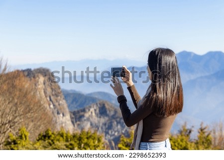 Woman take photo on cellphone of scenery view on the mountain 