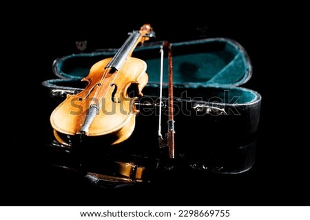 small model of an old violin with bag on black surface with black background