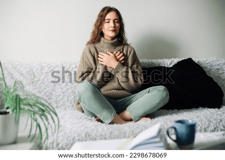 Relaxation techniques: Woman practicing pranayama in lotus position on bed, breathing exercises to reduce stress and anxiety, achieving inner balance and harmony, mindfulness and meditation practice Royalty-Free Stock Photo #2298678069