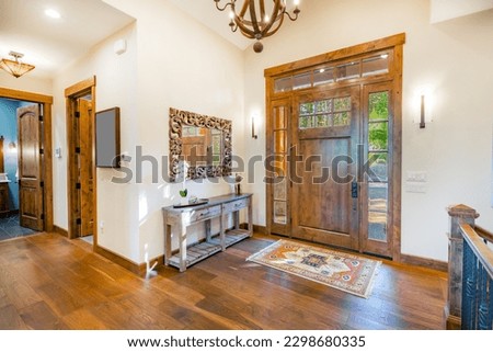 Elegant entryway and foyer with staircase rich dark wood tones stone wall on open door with gleaming hardwood floors area rug and a welcome atmosphere Royalty-Free Stock Photo #2298680335