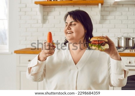 Overweight woman starts a healthy diet. Happy fat lady with a carrot and a hamburger in her hands smiles and chooses to eat vegetables. Choice between a healthy and unhealthy diet concept