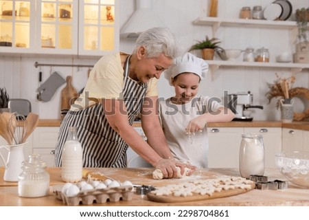 Happy family in kitchen. Grandmother and granddaughter child cook in kitchen together. Grandma teaching kid girl knead dough bake cookies. Household teamwork helping family generations concept Royalty-Free Stock Photo #2298704861