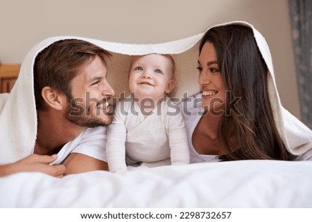 Happy family, parents and baby with blanket on bed for love, care and quality time together. Mother, father and playful newborn child relaxing in bedroom with bedding fort, smile and bonding at home Royalty-Free Stock Photo #2298732657