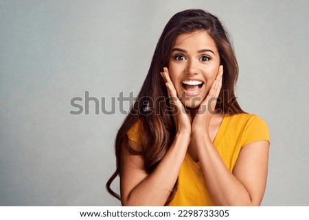 Gasp. Studio portrait of an attractive young woman looking surprised against a grey background.