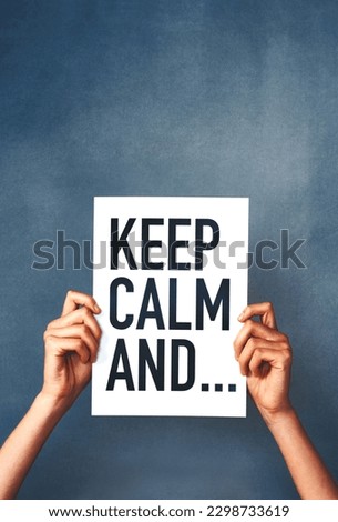 No need to get worked up. Studio shot of an woman holding a sign that says keep calm against a blue background.