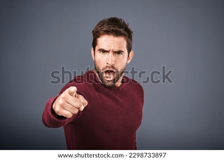 Who do you think you are. Studio shot of a handsome young man pointing a finger in anger against a gray background. Royalty-Free Stock Photo #2298733897