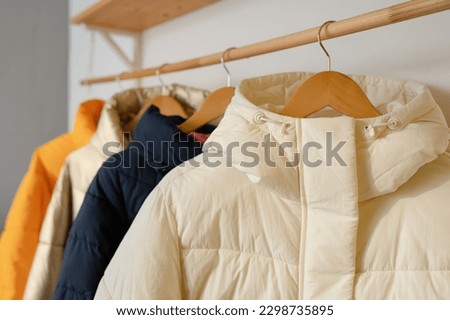Winter clothes on a hanger in the room. A row of down jackets hang on a white background. Royalty-Free Stock Photo #2298735895